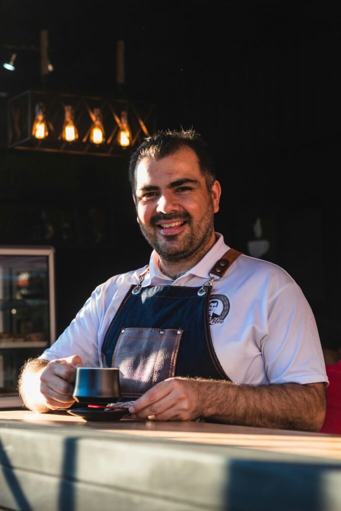 Freundlicher Cafébesitzer präsentiert eine Tasse Kaffee an einem Tresen